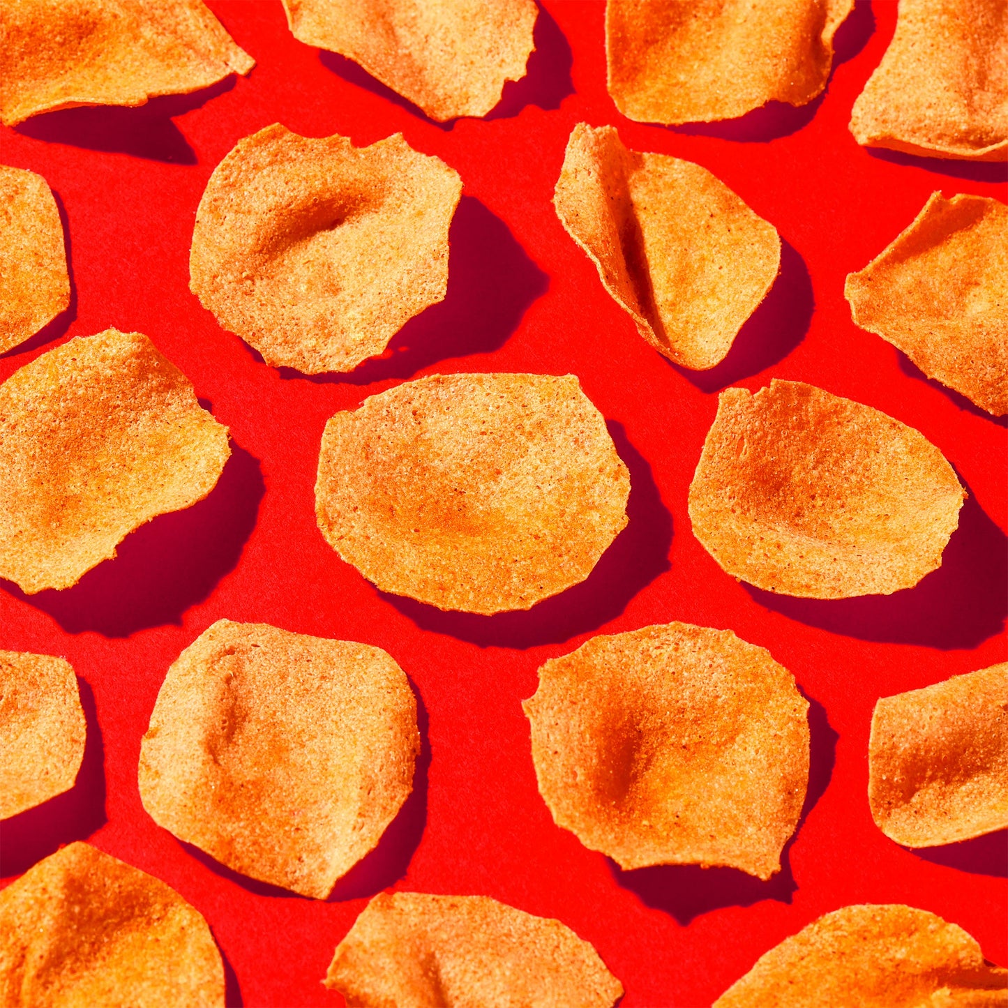 Reddish-orange Nashville Hot flavored chips arranged on a red background
