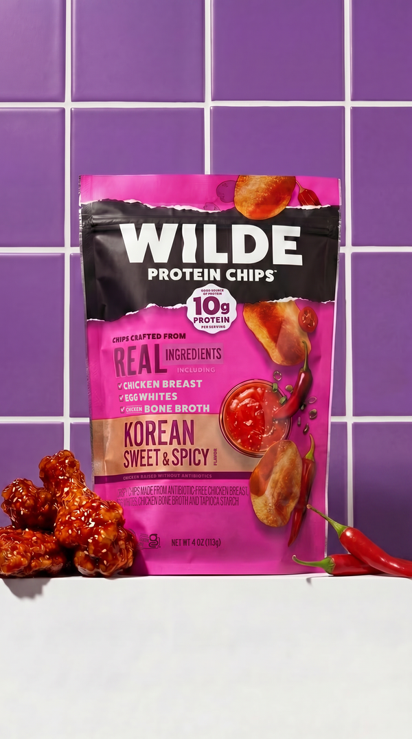 Front of Wilde Protein Chips Korean Sweet & Spicy bag with 10g protein badge, pink pack on purple tiled background
