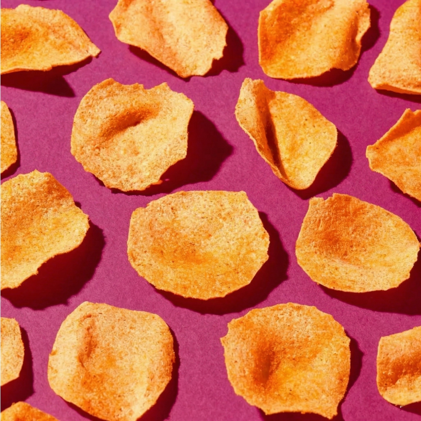 Overhead close-up of Korean Sweet & Spicy protein chips showing orange seasoned crisps on a purple background